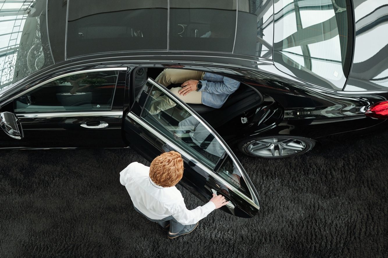 Professional driver assisting a passenger from above